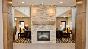 A lobby with a stone fireplace, wooden pillars, and a carpeted floor. - Accessible Studio Suite, 1 King with Tub (Humble)