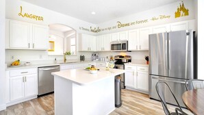A modern kitchen with white cabinetry, stainless steel appliances, and a central island. - SALT WATER POOL*EXPANSIVE POOL DECK* LED POOL FOUNTAIN JETS (kissimmee)