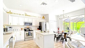 A modern kitchen with white cabinetry, stainless steel appliances, and a central island. - SALT WATER POOL*EXPANSIVE POOL DECK* LED POOL FOUNTAIN JETS (kissimmee)