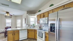 A modern kitchen with wooden cabinets, a stainless steel refrigerator, a microwave, and a dishwasher.