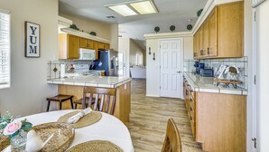 A kitchen with wooden cabinets, a central island, and a dining area with chairs and a table.