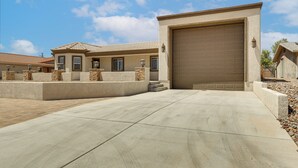 A residential driveway leading to a garage, with a house featuring a tiled roof and stone accents.