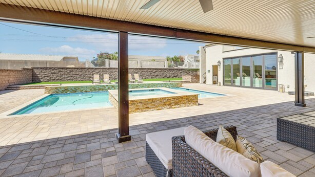 A covered outdoor area with a pool, seating, and a ceiling fan.
