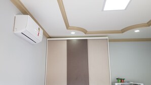 A bathroom with a white air conditioner, a beige and gray wall panel, and a ceiling with recessed lighting and a skylight.