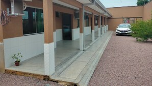 A building with a covered walkway, a car parked in front, and a small plant near the entrance.