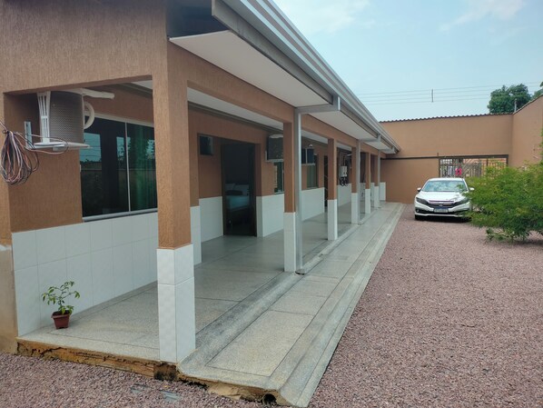 A building with a covered walkway, a car parked in front, and a small plant near the entrance. - Brand new suite with furniture, television, refrigerator, Netflix, Wifi. Come check...! (Floresta)