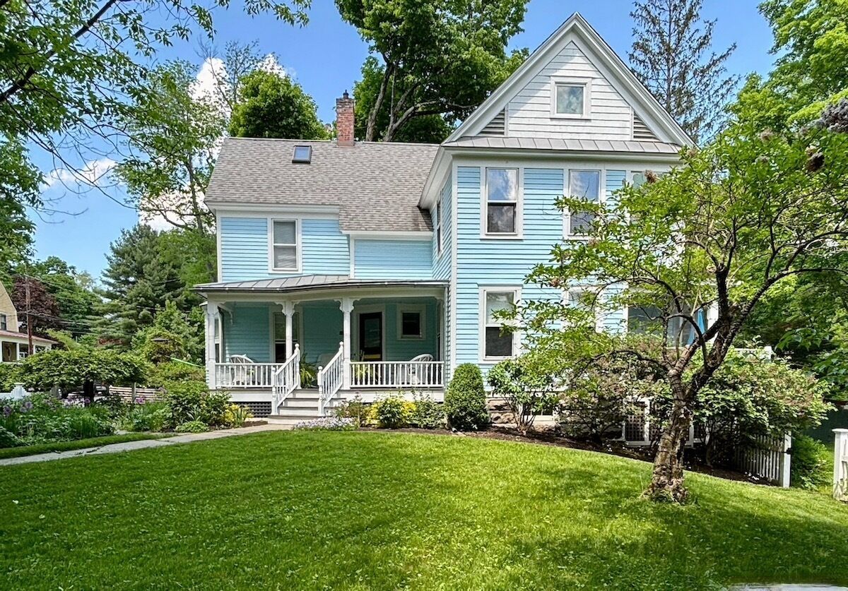 A two-story house with a porch and a well-maintained lawn.