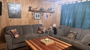Una sala de estar acogedora con una pared de madera, un sofá gris, una mesa de centro de madera y una lámpara.