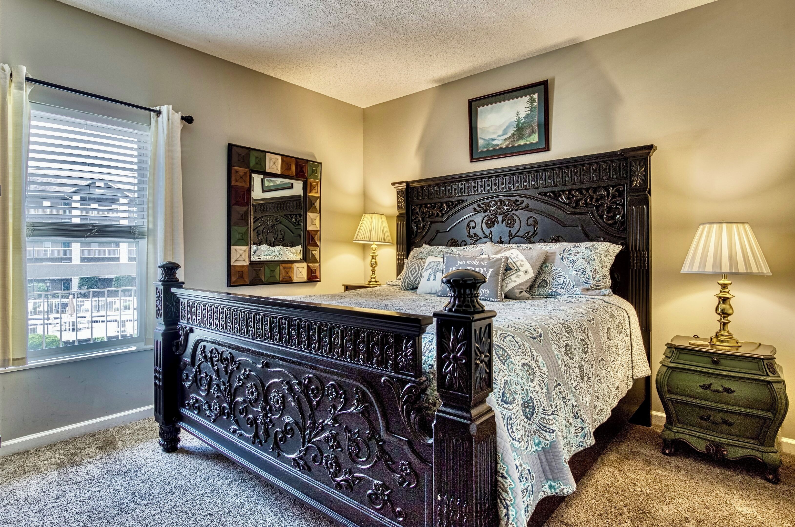 A bedroom with a dark wooden bed, a green nightstand, a window with blinds, and a wall-mounted picture.