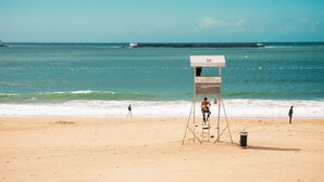 A lifeguard tower with a sign, beach, and ocean.