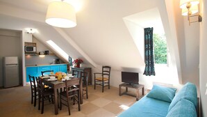 A compact living space with a dining area, kitchenette, and a sleeping area with a view.