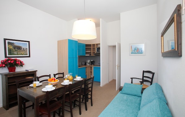 A compact living space with a dining area, kitchenette, and a sofa. - Studio avec Cuisine Equipée | Monument Historique (Erdeven)