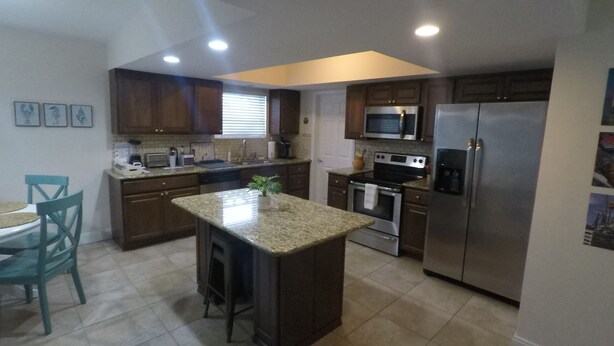 A modern kitchen with granite countertops, stainless steel appliances, and wooden cabinets.