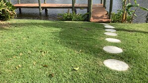 A grassy area with a wooden dock leading to a small boat docked on the water.