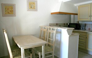 Uma cozinha compacta com mesa, cadeiras, micro-ondas e cafeteira.