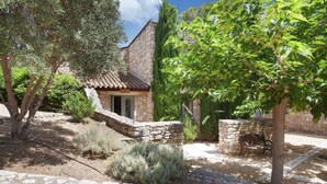 A stone building with a tiled roof, surrounded by trees and shrubs. - Appart Duplex avec Climatisation | 2km de Gordes (Gordes)