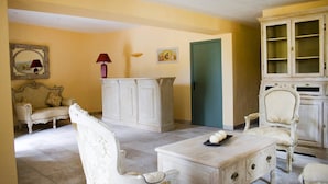 Una habitación con un sofá blanco, un armario blanco, un sillón blanco y una mesa de centro con adornos.