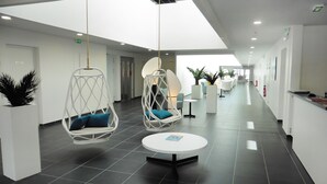 A modern lobby with hanging chairs, a reception desk, and a clean, tiled floor. - Apprt Equipé Près de la Plage! Piscine Saisonnière (Cap d'Agde)