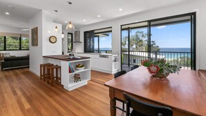A modern kitchen with a large island, wooden flooring, and a view of the ocean. - Beautiful Apartment built 2019 (Point Lookout)