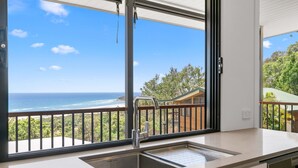 A kitchen with a large window overlooking a beach and a wooden deck. - Beautiful Apartment built 2019 (Point Lookout)