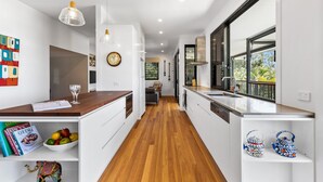 A modern kitchen with white cabinetry, wooden flooring, and a view to the outdoors. - Beautiful Apartment built 2019 (Point Lookout)
