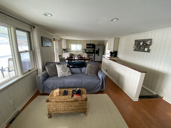 A cozy living room with a sofa, a coffee table, and a kitchen in the background.