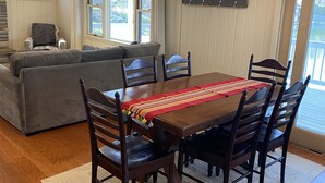 A dining area with a wooden table, six chairs, and a red-striped table runner. - Relaxing Lake House - Enjoy the Sun and Fun!!! (Erieville)