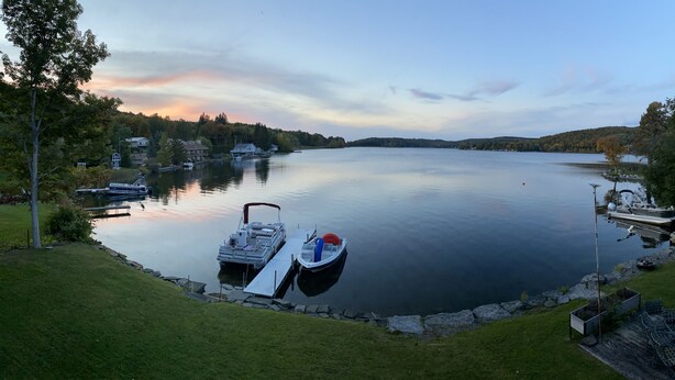 A calm lake with a dock, boats, and houses in the background. - Relaxing Lake House - Enjoy the Sun and Fun!!! (Erieville)