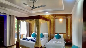 Habitación de hotel con dos camas, ventilador de techo y vistas al exterior.