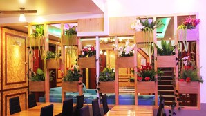 Un restaurante con muebles de madera, una escalera y macetas colgantes con flores.