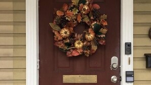 Une porte rouge ornée d’une guirlande décorative, une boîte aux lettres et un sonnette.