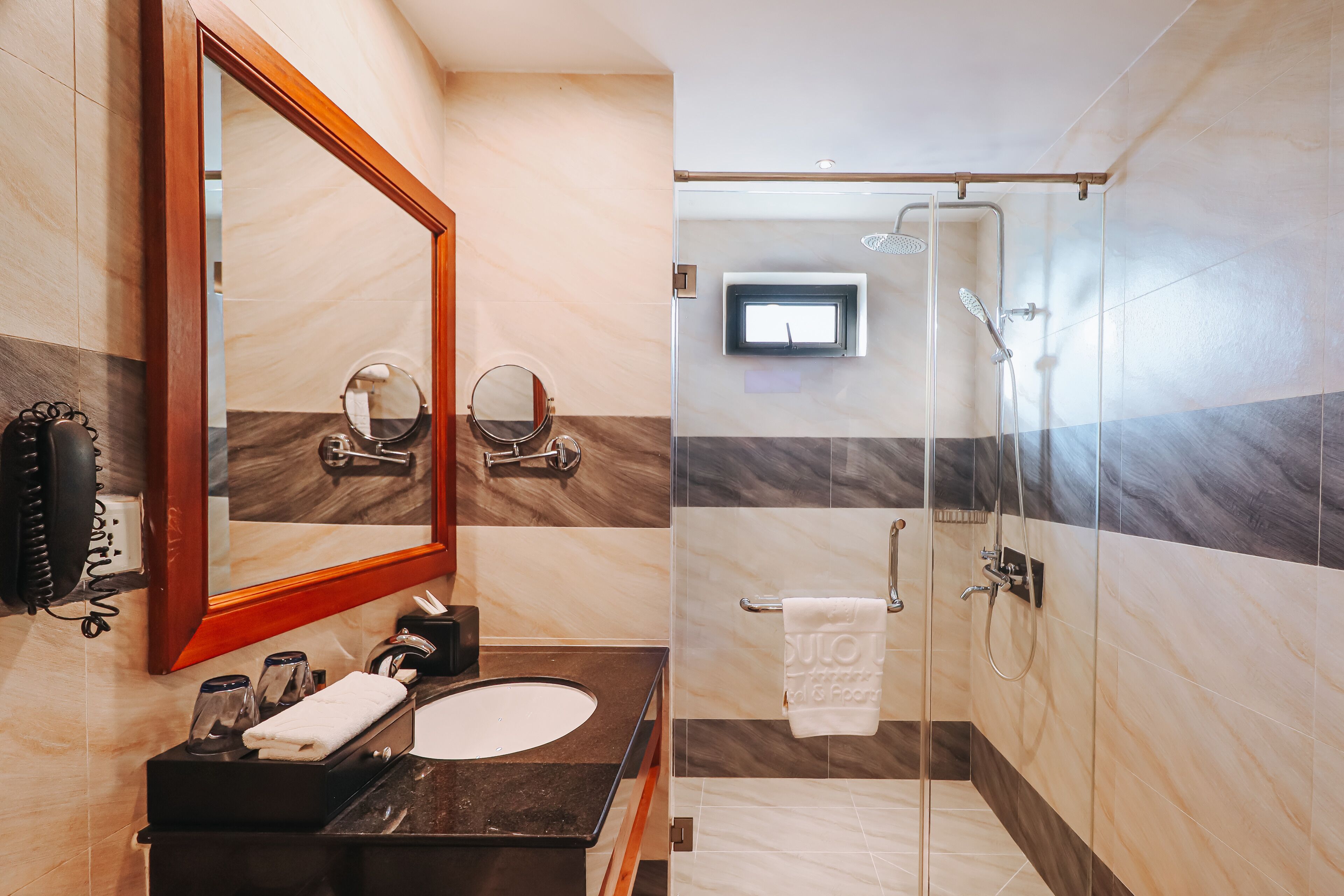 A modern bathroom with a marble vanity, a large mirror, a glass-enclosed shower, and a towel rack.