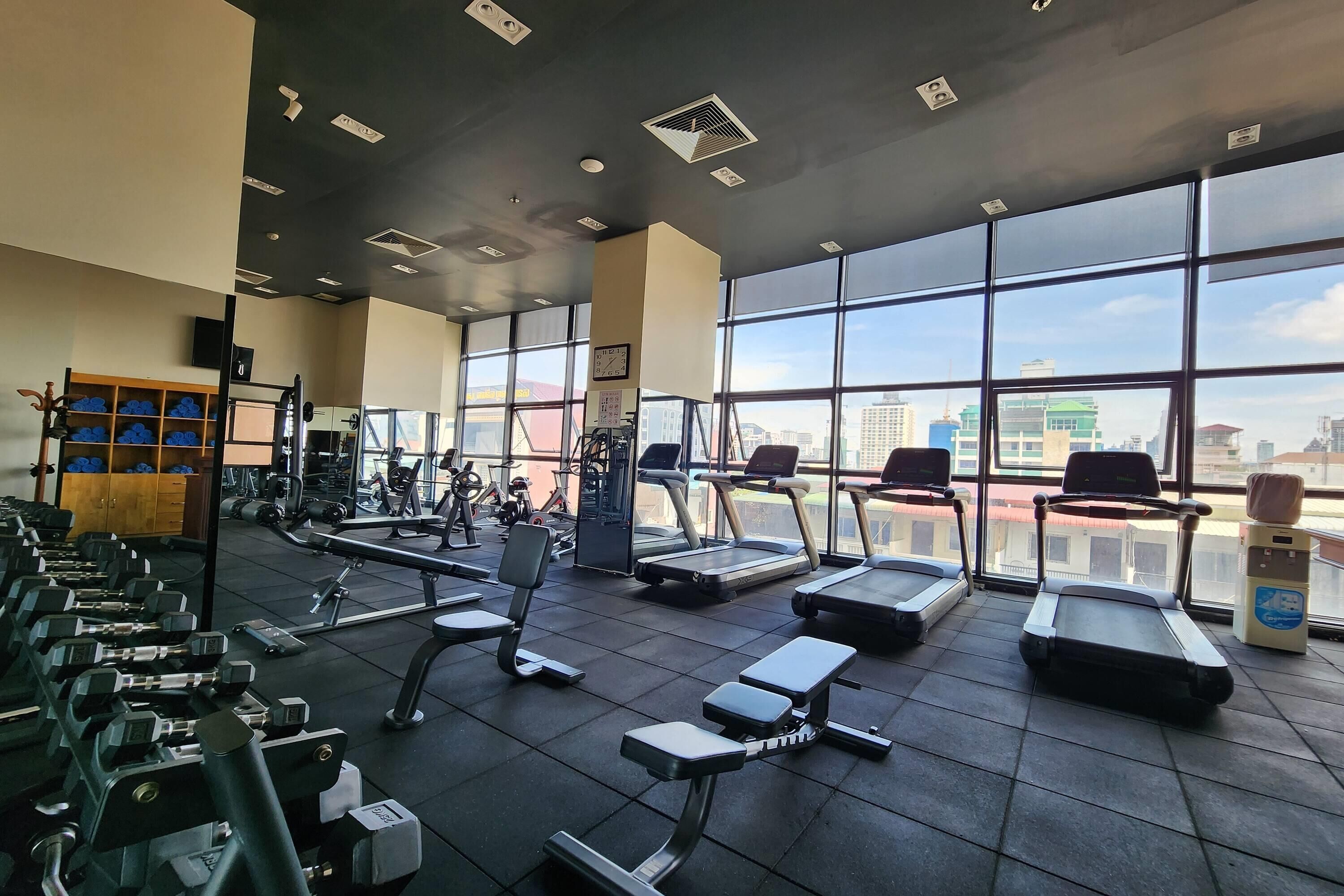 Un gimnasio con cintas de correr, mancuernas y máquinas de pesas.