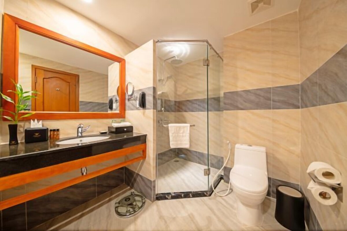 A modern bathroom with a glass shower enclosure, a sink with a mirror, and a toilet.