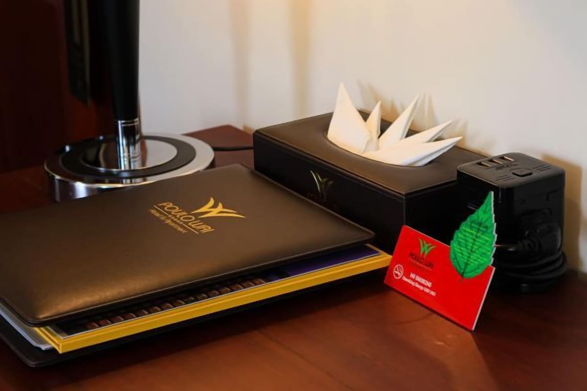 Una laptop, una caja de pañuelos y una tarjeta sobre una superficie de madera.