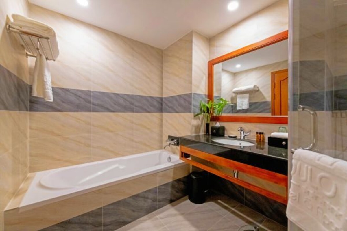 Une salle de bain moderne équipée d’une baignoire, d’un lavabo, d’un miroir et d’un porte-serviettes.