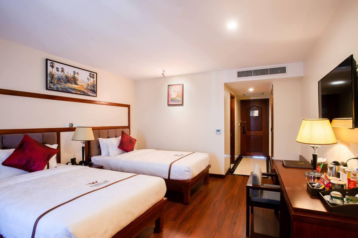 Una habitación de hotel con dos camas, un escritorio con lámpara y televisión.