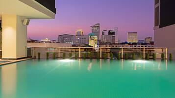 Una piscina al aire libre, sombrillas, sillones reclinables de piscina