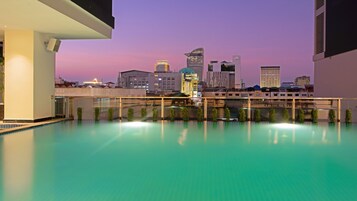 Una piscina al aire libre, sombrillas, sillones reclinables de piscina