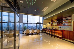 Un moderno bar d'albergo con ampie finestre, vista sulla città e interni curati.