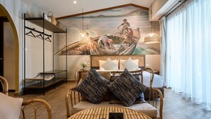 A room with a mural of fishermen, a bed with pillows, a round table, and a hanging light fixture. - Barabara Budget Satun (La-ngu)