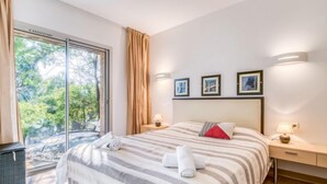 A hotel room with a large bed, a sliding glass door to a balcony, and three framed pictures on the wall. - Cala Sultana by Interhome (Porto Vecchio)