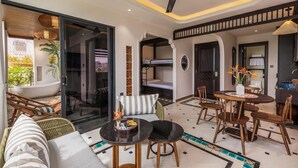 A modern living room with a sofa, dining table, and chairs. There is a ceiling fan, a large window, and a view of the outside. - Seahorse Tropical Natalie Da Nang Hotel by Haviland (Da Nang)