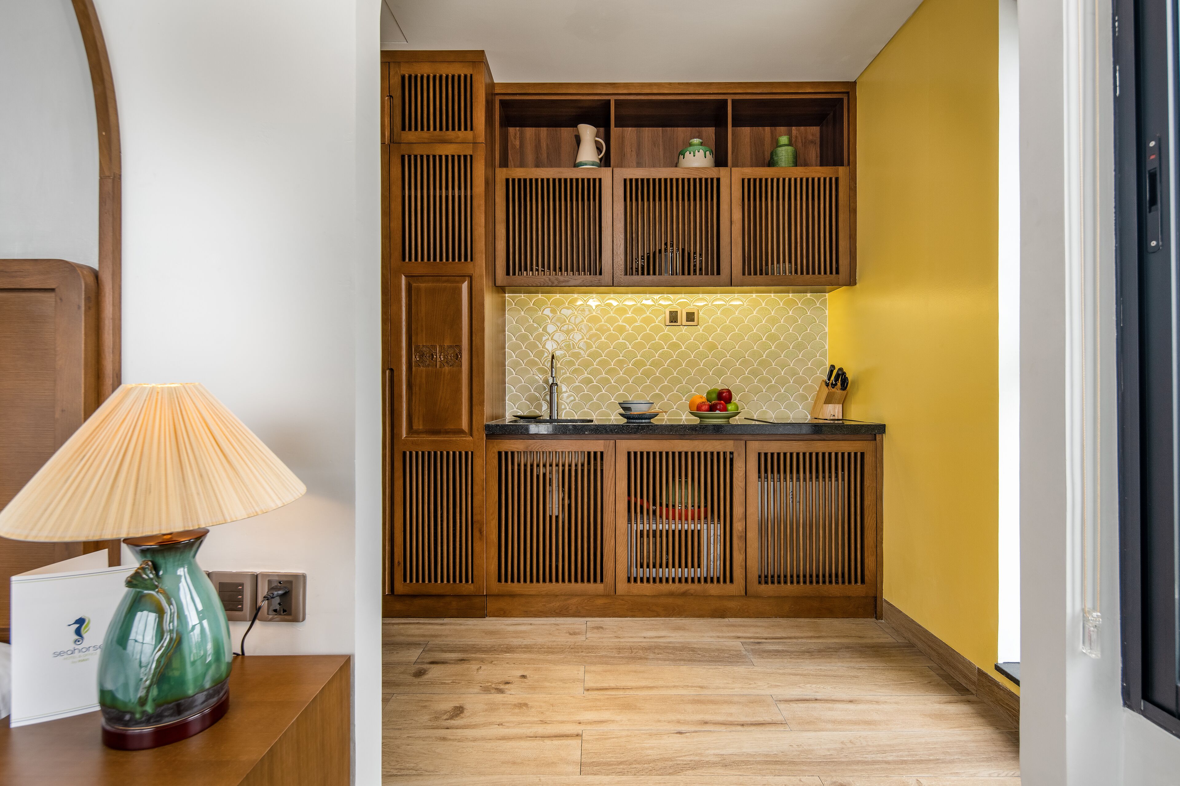 Una cocina con armarios de madera, salpicadero de azulejos y un frutero en la encimera.