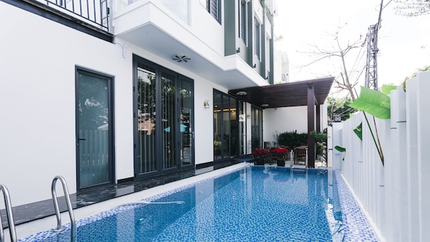 A modern building with a swimming pool, large windows, and a covered outdoor area. - Le Petit Villa Hoi An (Da Nang)