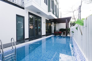 A modern building with a swimming pool, large windows, and a covered outdoor area. - Le Petit Villa Hoi An (Da Nang)