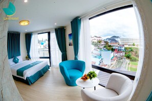 A hotel room with a bed, a blue armchair, a white armchair, and a small table with flowers.