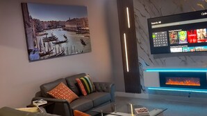 Moderni olohuone, jossa on sohva, takka ja televisio, josta näkyy elokuvavalikoima.