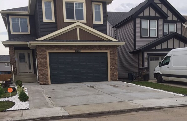 A two-story house with a garage, a driveway, and a white van parked in front.