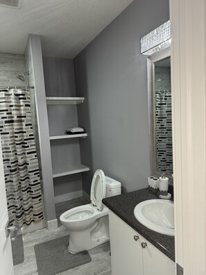 A modern bathroom with a toilet, sink, and shower.